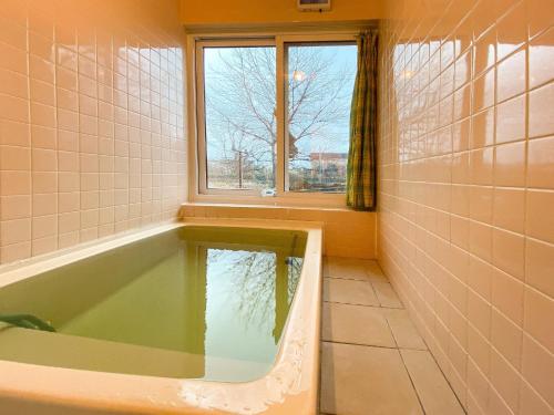 a bathroom with a bath tub with a window at Kojohama base - Vacation STAY 89929v in Shikyū