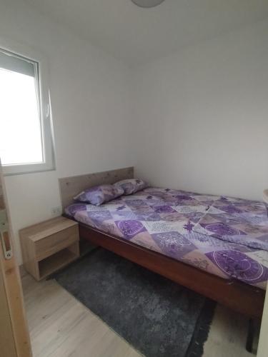 a bedroom with a bed with a purple comforter and a window at Vaske in Bar