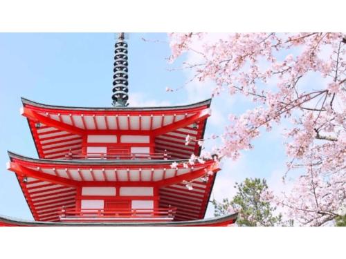 a red building with pinkakura trees in the foreground at Asama no Iori - Vacation STAY 00999v in Fujiyoshida