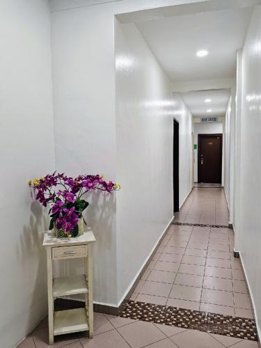 a hallway with a vase of flowers on a table at G Six Hotel in Sitiawan
