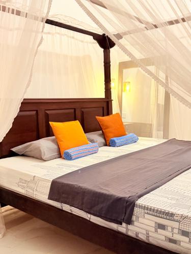Una cama con dos almohadas de color naranja y azul. en Green Palace Mirissa, en Mirissa