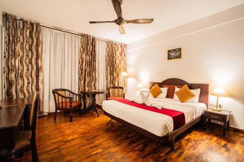 a bedroom with a bed and a desk in a room at Hotel C7 Munnar in Munnar