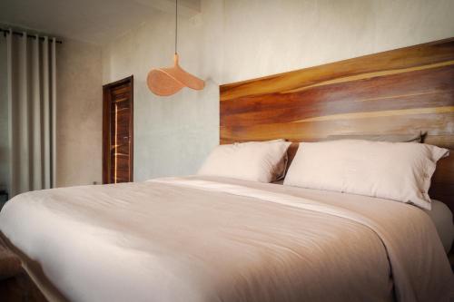 a bedroom with a large white bed with a wooden headboard at MUUN Beach Club in Ciudad del Carmen