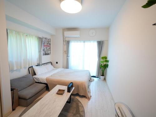 a bedroom with a bed and a couch and a table at REVISION Kairouyama-tei - Vacation STAY 15800 in Hiroshima