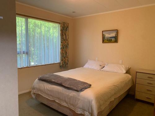 a bedroom with a large bed and a window at Tranquil Tides in Motueka