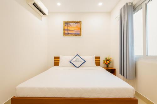 a bedroom with a large white bed with a window at Lunaria Maison - Thư Thái Homestay in Ho Chi Minh City