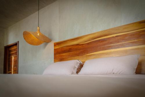 a bedroom with a bed with a wooden headboard and two pillows at MUUN Beach Club in Ciudad del Carmen