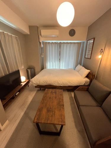 a bedroom with a bed and a couch and a table at REVISION Ebiyama-tei - Vacation STAY 17794 in Hiroshima