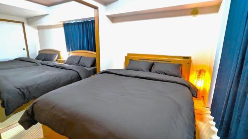 two beds in a small room with blue curtains at Space Minami 4jo - Vacation STAY 17247 in Sapporo