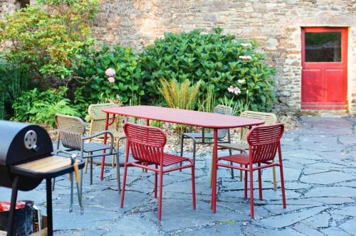 a red table and chairs with a red door at De rulinen in Saint-Clet