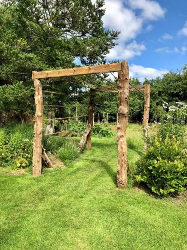 an arch made out of logs in the grass at De rulinen in Saint-Clet