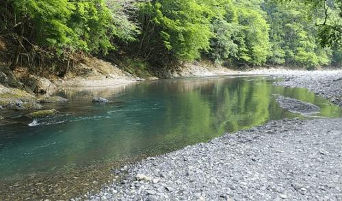 einen Fluss mit felsigem Ufer und Bäumen im Hintergrund in der Unterkunft Ryujin Village Oku-Komatagawa Bungalow - Vacation STAY 42249v in Ōkuma