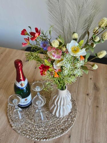 a vase with flowers and wine glasses on a table at Ferienwohnung Waldblick in Oberthal