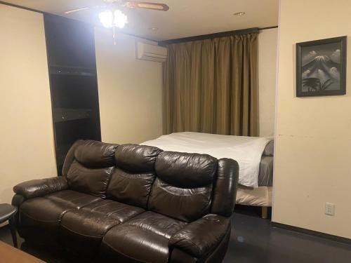 a living room with a leather couch and a bed at Kami no Tsuki - Vacation STAY 15816 in Akiruno
