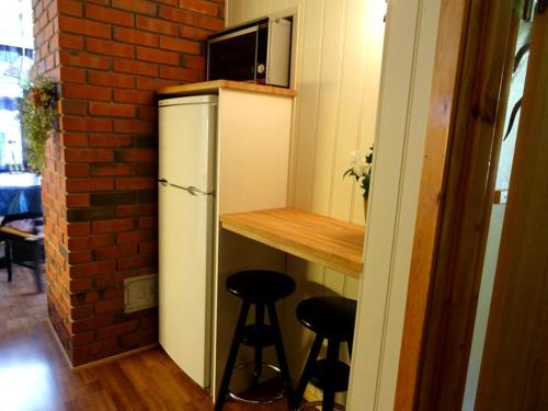 a small kitchen with a refrigerator and bar with stools at Actif 413 - apartment close to Ål Ski Centre in Ål