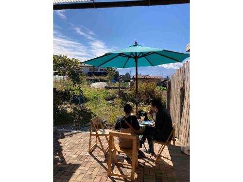 a man and a woman sitting at a table under an umbrella at LongHillsEcoGuesthouse&Cafe - Vacation STAY 24885v in Kinoshita