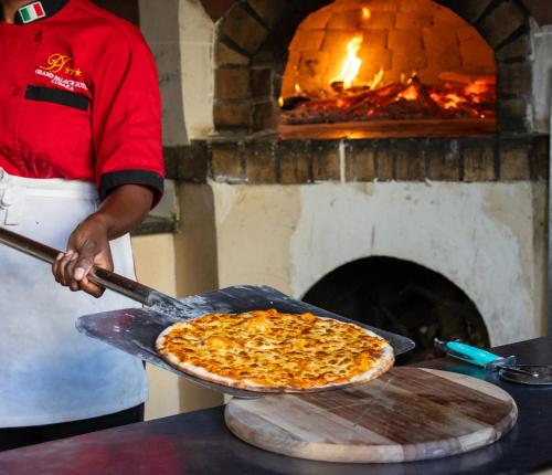 a person holding a pizza in front of an oven at Grand Palace Hotel Lusaka in Lusaka