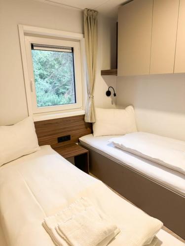 two beds in a small room with a window at Lakeside Petzen Glamping in Unterlibitsch