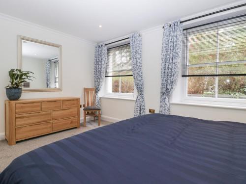 a bedroom with a bed and a dresser and two windows at Flat 2 Battledown Grange in Cheltenham
