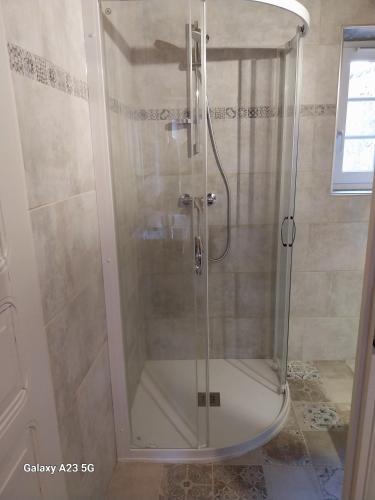 une douche avec une porte en verre dans une salle de bain dans l'établissement Le Petit Chapître, à Belvès