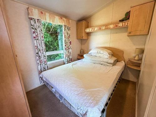 a small bedroom with a bed and a window at 8 Berth Spacious Dog Friendly Caravan, Near Great Yarmouth In Norfolk Ref 10004G in Belton
