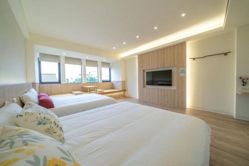 a bedroom with two beds and a flat screen tv at 慶東雙包棟招待所 兩棟可選擇包層包棟 可住4-70人 團體聚會首選 in Tainan
