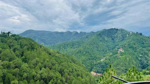 vista su una catena montuosa con alberi e case di Mayank homestay shimla a Shimla