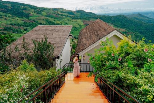 a woman in a dress walking down a wooden bridge at Baan Rai good view cafe&Resort in Mae Suai