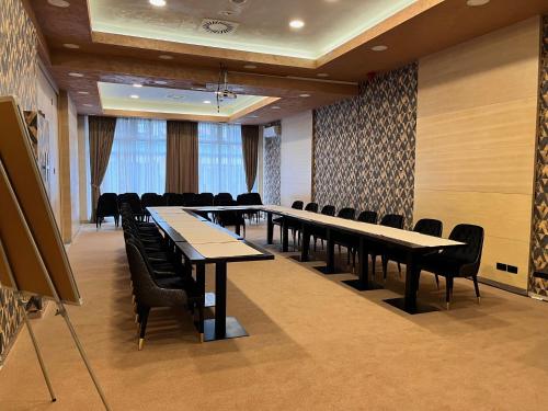 a conference room with long tables and chairs in it at Hotel Monogram Park in Ruma