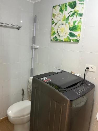 a bathroom with a toilet and a picture on the wall at DaLei 1-319 Sleeps 8pax at Marina Spatial Condominium in Dumaguete City in Dumaguete