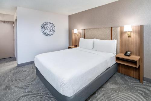 a hotel room with a large bed with white sheets at Holiday Inn Dublin - Pleasanton by IHG in Dublin