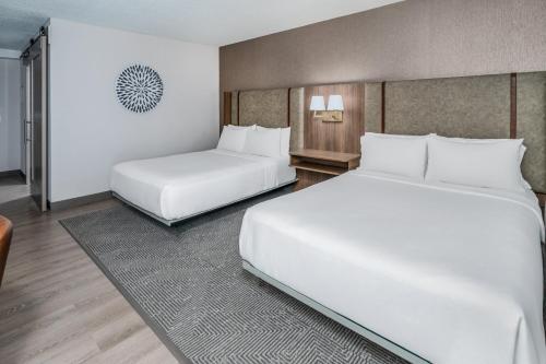 two beds in a hotel room with white sheets at Holiday Inn Dublin - Pleasanton by IHG in Dublin