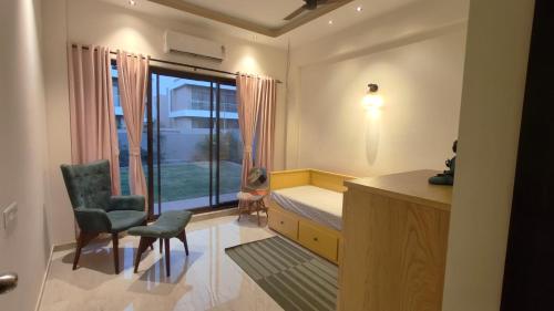 a bedroom with a bed and a window and a chair at Cozy 3BHK Villa with a Private Lawn - Karjat in Dhamni