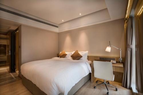 a bedroom with a bed and a desk and a chair at 郑州豪锦汇酒店 Zhengzhou Haojinhui Hotel in Zhengzhou