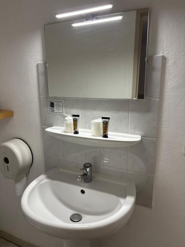 a bathroom with a white sink and a mirror at Le Saint Vincent in Apremont