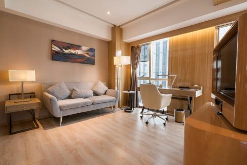 a living room with a couch and a desk at 郑州豪锦汇酒店 Zhengzhou Haojinhui Hotel in Zhengzhou