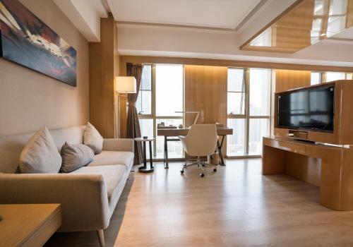 a living room with a couch and a television at 郑州豪锦汇酒店 Zhengzhou Haojinhui Hotel in Zhengzhou