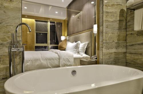 a bathroom with a bath tub and a bed at 郑州豪锦汇酒店 Zhengzhou Haojinhui Hotel in Zhengzhou