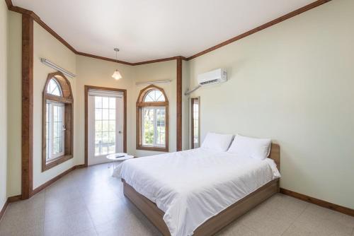 une chambre avec un grand lit et deux fenêtres dans l'établissement Santa Beach Pension, à Kangmun