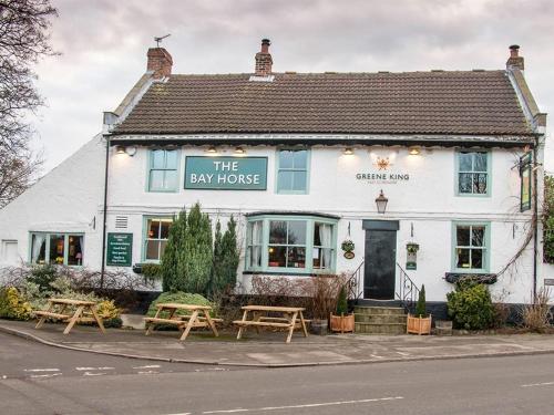 a white inn with picnic tables in front of it at The Bay Horse Inn in Green Hammerton
