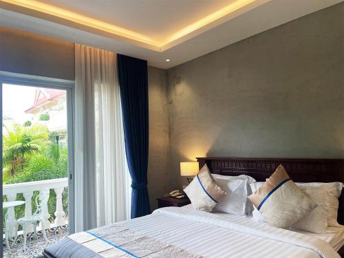 a bedroom with a bed and a large window at Sokchea Kampot Hotel in Kampot
