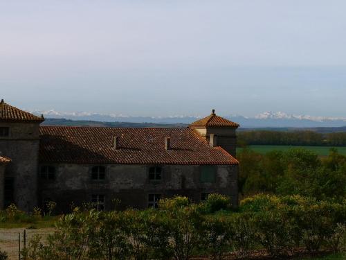 an old building with red tile roofs with mountains in the background at Le regard du château - Pierre et design premium in Alzonne