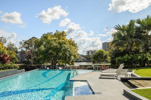 a swimming pool with chaise lounge chairs and trees at Riverside Lux 2Bed 2Bath Parking in Brisbane