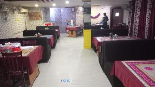 a dining room with tables with red table cloths at Hotel Shristy Residency in Dhanbād