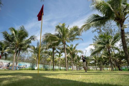a man is playing golf with a red flag at Wyndham Garden Grandworld Phu Quoc in Phu Quoc
