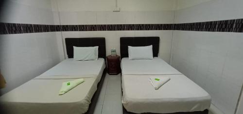 Dos camas en una habitación pequeña con sábanas blancas. en E657 SERi TERUNTUM, en Kuantan