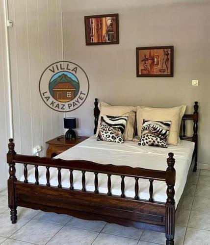 a bedroom with a wooden bed with pillows on it at VILLA LA KAZ PAYET in Rivière