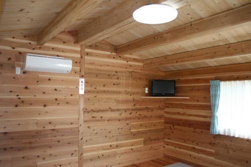 a room with a wooden wall with a tv in it at Tokai Beach Outdoor Campsite Mori no Shonen Oji - Vacation STAY 42348v in Noma