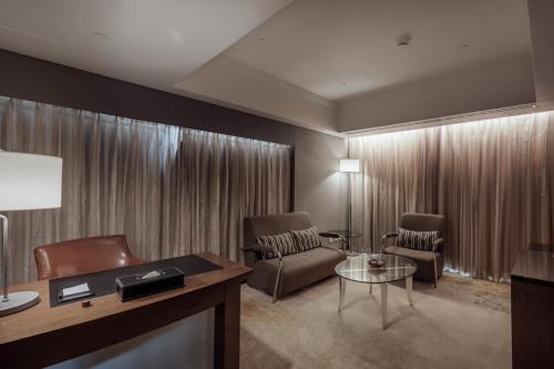 a living room with a couch and chairs and a table at Evergreen Plaza Hotel - Tainan in Tainan