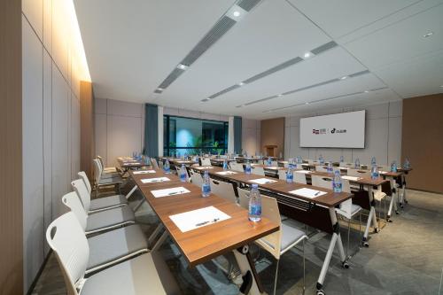 a conference room with wooden tables and white chairs at Yizhi Hotel - Guangzhou Shamian Island Huangsha Metro Station-Canton Fair free shuttle bus included Breakfast in Guangzhou